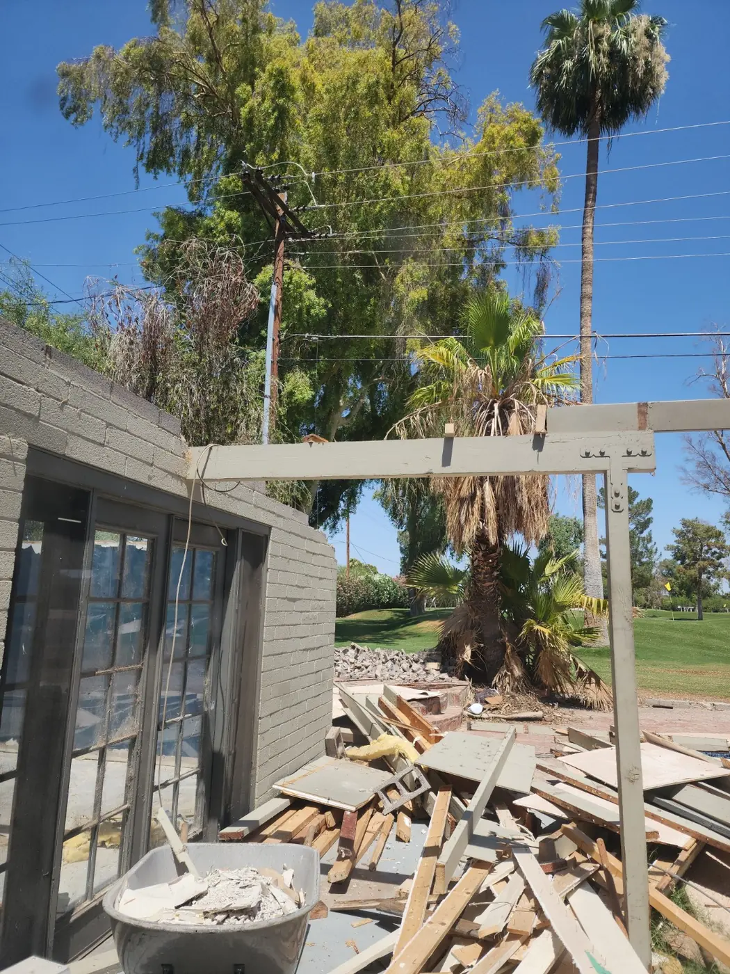 Exterior room demolition in progress with debris staged for hauling